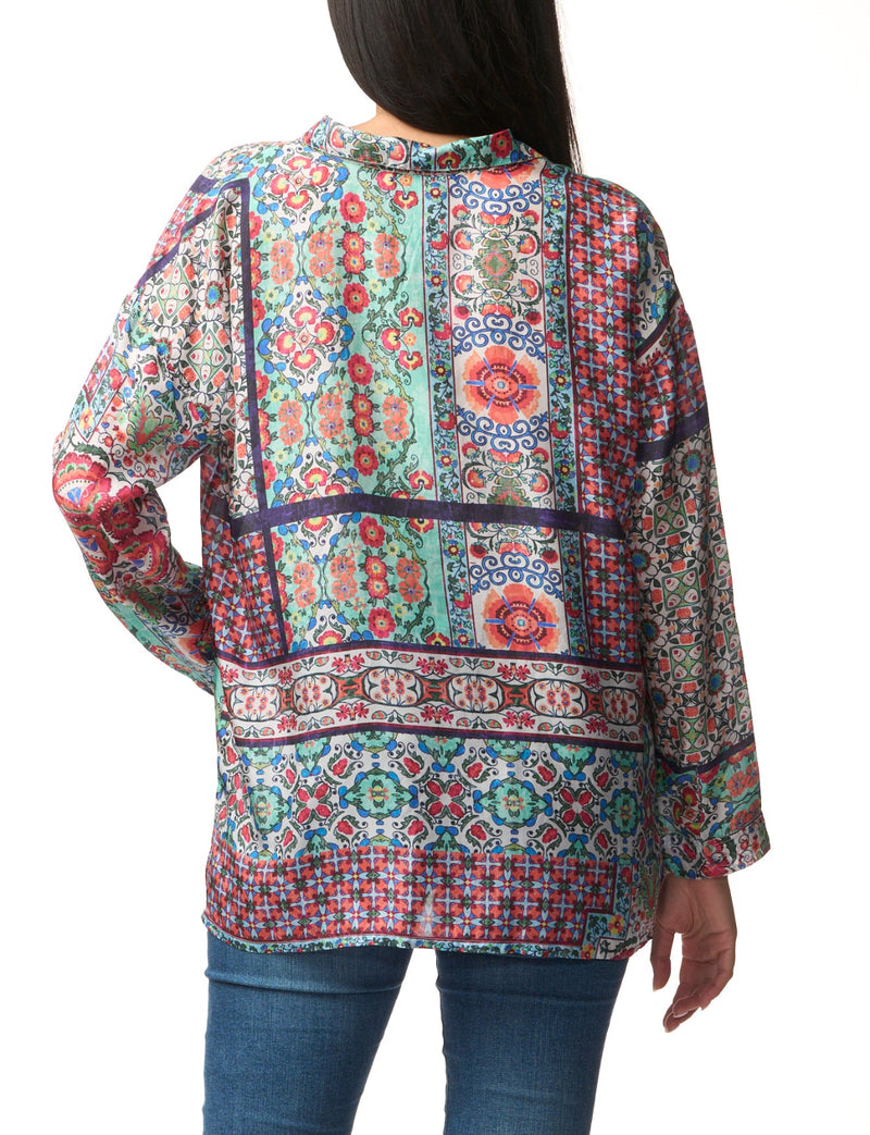 Multicolored patterned blouse worn by a person on a white background