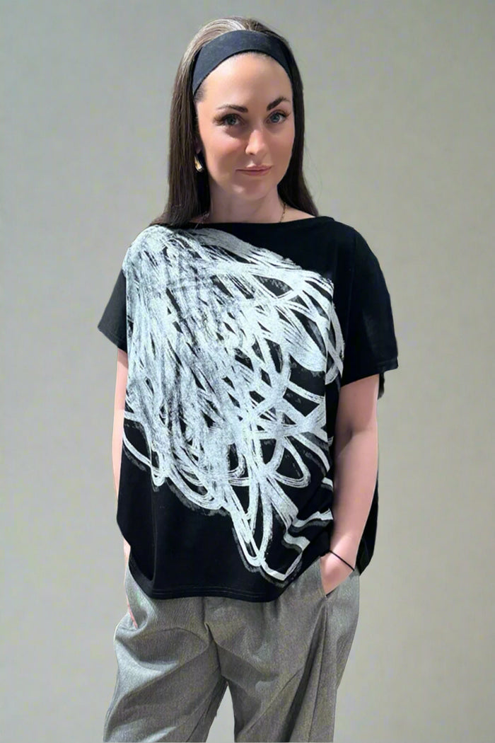 Woman wearing a black and white abstract design top in a store setting
